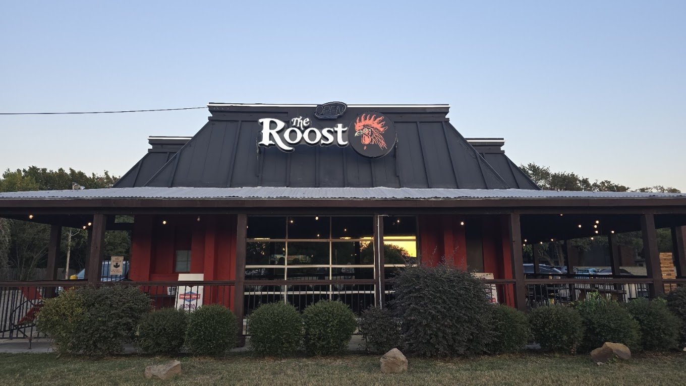 Exterior of The Roost Lewisville at dusk with covered patio and rooster sign